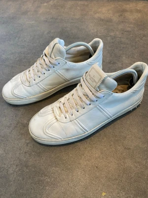 Valentino Flycrew - Säljer ett par stilrena Valentino Garavani sneakers i vitt läder. Passar till i princip allt. Skorna är använda och har normalt slitage i form av veck i lädret samt lite smuts på sulorna (se bilder)                                                            Hör gärna av dig vid frågor eller om du vill ha fler bilder! Går ner i pris vid snabbaffär🤩