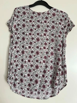 Blus/tröja med blommor - Superfin tröja/blus med vackra blommor på. Tycker denna är så fin men den kommer tyvärr aldrig till användning här hemma.   Den är liten i storleken. Mått här:  Längd: fram ca 57cm / bak ca 62 cm Axelbredd: ca 36 cm  Jag som är XS/S tycker den sitter perfekt på.