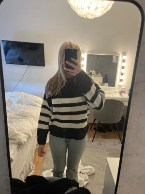 Stickad tröja från Gina tricot - Snygg stickad tröja med breda svarta och vita horisontella ränder. Tröjan har lång ärm, rund halsringning och ribbade muddar vid ärmslut och nederkant. Perfekt för dig som gillar klassisk men trendig stil.