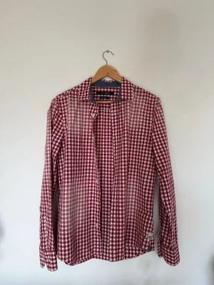 Rutig slim fit skjorta - Röd/Vit - Vit/röd rutig skjorta från KappAhl i Slim Fit. Klassisk krage och lång ärm med justerbara manschetter. Snygg och lättmatchad skjorta som passar både till vardagen och lite mer uppklätt. Mycket fint skick - använt två gånger.