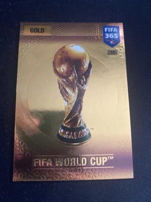 FIFA World Cup guld samlarkort - Säljer ett exklusivt guldigt samlarkort med FIFA World Cup-motiv från FIFA 365-serien. Kortet har en skimrande guldfinish och visar VM-pokalen i mitten. Perfekt för dig som gillar fotboll och samlar på unika kort.