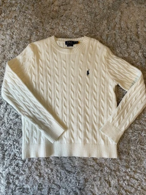 Polo - Klassisk svart kabelstickad tröja från Ralph Lauren. Mjukt material med ikonisk broderad häst på bröstet. "Custom Fit". Perfekt för alla tillfällen.