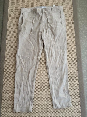 Beige linnebyxor  - Snygga beige linnebyxor med avslappnad passform och dragsko i midjan. Byxorna har sidfickor fram och två fickor bak. Perfekta för en chill och luftig stil under varma dagar. Bra skick storlek 44