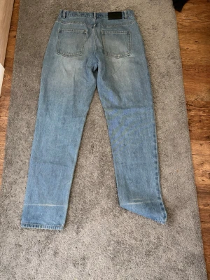 Ljusblå raka jeans - Säljer ett par klassiska ljusblå jeans med raka ben och femficksmodell. Jeansen har en något hög midja och är tillverkade i denim. Perfekta för en avslappnad stil.
