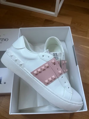 Vita och rosa Valentino sneakers  - Säljer ett par vita Valentino sneakers från som jag har köpt här på Plick för ett tag sen. Säljaren sa att de var äkta men är ej helt säker. Köpte de själv för 1600 men säljer de för mindre eftersom jag ej kan garantera äktheten. Använd 1 eftersom de är för små för mig. Det är bara att skriva om man har en fråga!💕