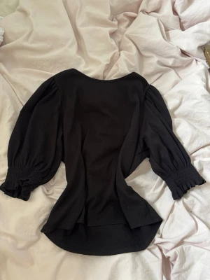Svart topp med puffärmar - Säljer en svart topp med voluminösa puffärmar. Toppen har en rund halsringning och är lätt figursydd för en snygg siluett. Perfekt för dig som vill ha en enkel men trendig look. Skriv vid frågor eller funderingar 💕