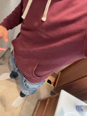 Vinröd hoodie  - Säljer en vinröd hoodie med huva och vita dragsnören. Hoodien har en stor magficka framtill och ribbade muddar vid ärmslut och nederkant. Tillverkad i mjukt bomullsliknande material, perfekt för chill dagar.