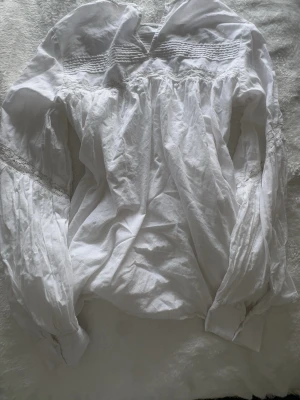 Vit blus med spetsdetaljer | odd Molly - Söt vit blus med långärmad design och fina spetsdetaljer längs ärmarna och bröstet. Blusen har rynkade partier och dekorativa veck upptill som ger en vintagekänsla. Tillverkad i ett tunt, mjukt tyg som känns luftigt och bekvämt.