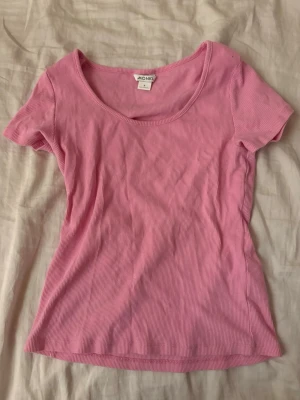 Rosa ribbad t-shirt  - Säljer en söt rosa ribbad t-shirt från Monki i storlek S. T-shirten har korta ärmar, rund halsringning och är gjord i mjuk bomull. Perfekt att styla med jeans eller kjol för en chill look.