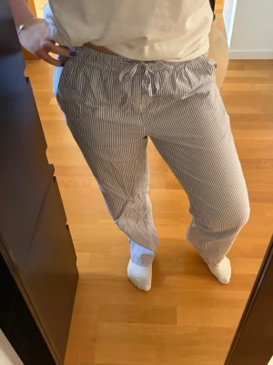 Randiga loungewear-byxor  - Säljer ett par avslappnade loungewear-byxor med tunna blå och vita ränder. Byxorna har resår och knytning i midjan. Tillverkade i ett mjukt och lätt material, perfekta för chill dagar. Skriv pm vid funderingar!☺️