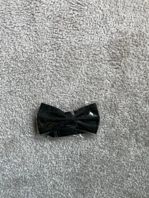 Svart fluga med diskret mönster - Snygg svart fluga med ett diskret, elegant mönster. Perfekt accessoar för att lyfta din outfit. Flugan är förknuten och levereras i plastförpackning. Materialet ser ut att vara polyester.