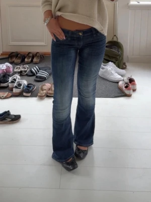 Blå bootcut jeans från cheap monday  - Säljer ett par blå bootcut jeans med låg midja. Jeansen har snygg tvätt med slitningar och är tillverkade i denim med lite stretch för skön passform. Perfekta till sneakers eller boots.
