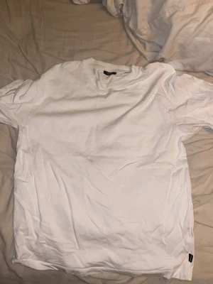 Vit t-shirt från Jack & Jones - Klassisk vit t-shirt från Jack & Jones med rund halsringning och normal passform. Tillverkad i mjuk bomull som känns skön mot huden. Perfekt basplagg för alla tillfällen och enkel att matcha med andra plagg.