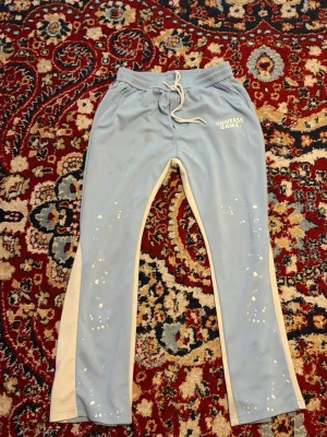 Universe Game Light Blue Track Pants / Joggers - Light blue Universe Game joggers with white side detailing and paint-splatter design. Great streetwear/casual fit. Condition: Good Size: [M] Colour: Light blue