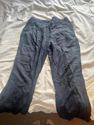 Svarta linnebyxor från 157 - Ett par lite mörkare marinblå linnebyxor från 157 med resår i midjan och dragsko. Byxorna har raka ben och är tillverkade i ett mjukt och bekvämt material, perfekta för chill dagar hemma eller när du vill ha det extra bekvämt. Kommer inte till användning.