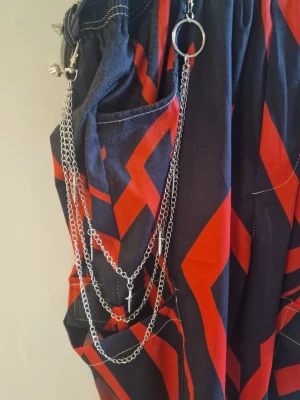 Byxkedja svärd - Byxkedja punk med svärd hänge. Innerkedja 41 cm. Mellankedja 49,5 cm. Ytterkedja 54,5 cm.