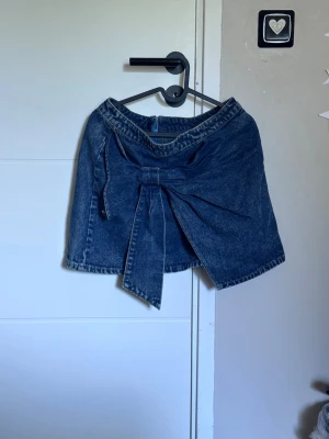 Dekorerad jeanskjol - Fin jeanskjol med rosett på och en kedja där bak