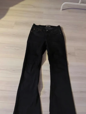 Svarta bootcut jeans - Säljer ett par svarta bootcut jeans med klassisk femficksmodell. Jeansen har vida ben och är tillverkade i ett stretchigt denimtyg som ger en snygg passform. Perfekta för dig som gillar en retroinspirerad look.