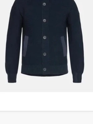 Henro cardigan med knappar  - Mysig mörkblå stickad kofta med stora knappar framtill och två fickor med kontrasttyg. Långärmad modell med ribbade muddar och nederkant. Perfekt för lager på lager och enkel att matcha med olika outfits.