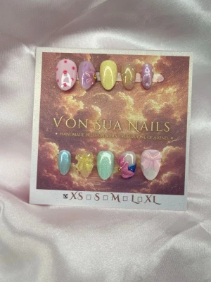 Miyju (XS);ExtraShortAlmond  - Ett lekfullt set i Extra Short Almond med mjuka pasteller och en drömmig jelly-finish. Varje nagel har sin egen lilla detalj – från körsbär och blommor till rosetter, skimmer och handmålade 3D-detaljer. En mjuk och fantasifull design där varje nagel får sin egen karaktär.  Handgjort av mig – varje set är unikt.  XS: 14 mm, 11 mm, 11,5 mm, 10 mm, 8 mm