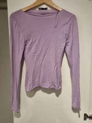 Ljuslila långärmad topp från Zara - Säljer en enkel och stilren ljuslila långärmad topp med rund hals. Toppen har en slim passform och är tillverkad i ett mjukt, stretchigt material som känns skönt mot huden. Perfekt att matcha med jeans eller kjol för en clean look.