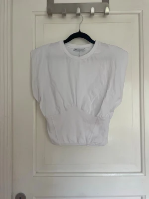 Vit topp Zara - Jättesnygg, vit, topp ifrån Zara! Passformen är lite lösare där uppe och tajtare i midjan, men hjälp av ett spänne i ryggen. Nästan aldrig använd då den är lite för liten för mig. Skriv vid funderingar eller egna prisförslag!💗