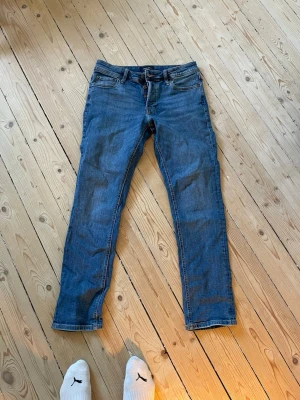 Blå raka jeans med klassisk passform - Säljer ett par blå jeans med rak passform och normal midja. Jeansen har fem fickor, bälteshällor och stängs med dragkedja och knapp. Materialet är klassisk denim i bomull. Perfekta till vardagslooken och funkar året runt. Mycket stretch material