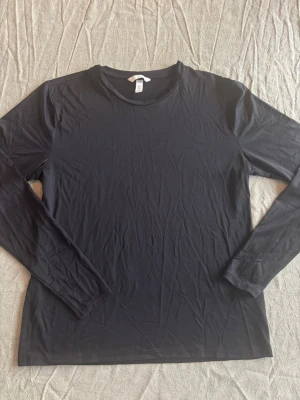 Svart långärmad topp - En enkel och stilren svart långärmad topp med rund hals. Tillverkad i ett mjukt och stretchigt material som passar perfekt till alla typer av outfits. Perfekt basplagg för garderoben.