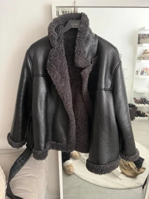 Svart teddyjacka från Gina Tricot - Säljer en svart teddyjacka från Gina Tricot med mjukt, fluffigt foder och krage i teddy. Jackan har en oversized passform, breda ärmar och detaljer i samma material vid ärmslut och nederkant. Perfekt för kalla dagar och riktigt snygg till alla outfits.