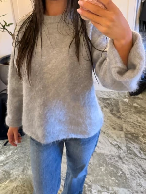 Ljusgrå fluffig stickad tröja - Mysig ljusgrå stickad tröja med fluffig yta och rund hals. Tröjan har långa ärmar och en avslappnad passform, perfekt nu till hösten. Från hm premium kollektion i mohair. Kosta 800 ny, inga defekter och är väl behållen. Jag är 165 som referens. Skriv privat för fler bilder.