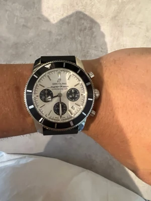 44mm Superocean kronografklocka - Snygg  Superocean kronografklocka med silverfärgad urtavla, svarta subdials och svart vridring. Klockan har en robust boett i stål och ett svart texturerat armband. Perfekt för dig som gillar klassisk men sportig stil.