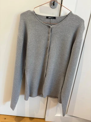 Grå kofta från Gina Tricot - Stilren grå kofta från Gina Tricot med rund halsringning och knäppning framtill. Långärmad modell i mjukt, tunt stickat material som passar perfekt till lager på lager. Enkel och tidlös design som är lätt att matcha.
