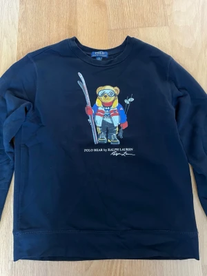 Ralph Lauren polo bear sweatshirt  - Svart tröja från polo bear Ralph Lauren i storlek 14-16 år. Tröjan är i mycket bra skick och har inga tecken på användning. Nypris på liknande tröjor är mellan 1000-2000 kronor. Hör av er vid frågor, pris kan diskuteras.