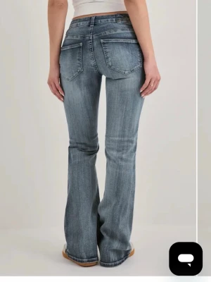 Blå bootcut jeans med slitningar - Nypris 699kr 🤍Säljer ett par blå bootcut jeans med lätt slitna detaljer och klassisk femficksdesign. Jeansen har normalhög midja och är tillverkade i ett mjukt denimtyg med lite stretch för skön passform. Perfekta för dig som gillar en avslappnad men trendig look. 