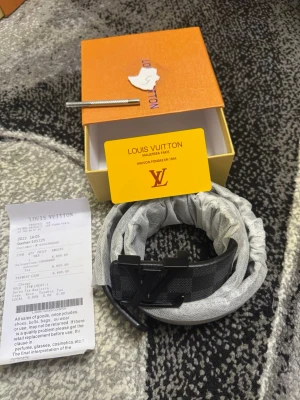 Svart LV bälte i skinn - Snyggt svart bälte från LV i skinn med klassiskt LV-spänne. Bältet har diskret rutigt mönster. Perfekt accessoar för att lyfta din outfit.