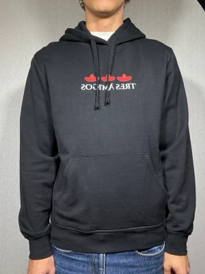 Tres amigos hoodie M - Hej och välkommen till byTorén. Detta är en hoodie från humorgruppen Tres Amigos i storlek M med normal passform. Modell på bild är ca 182, 67kg. Plagget är i bra skick utan några defekter. Tveka inte på att höra av dig, även om det skulle vara minsta lilla;)