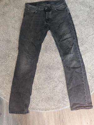 Svarta slim fit jeans - Snygga svarta slim fit jeans med klassisk femficksdesign och diskreta slitningar. Jeansen har raka ben och detaljerade sömmar på bakfickorna. Perfekta för en avslappnad och trendig stil.