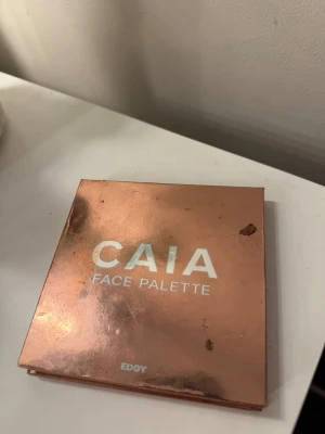 CAIA Face Palette Edgy - Säljer en CAIA Face Palette i färgen Edgy. Paletten innehåller fyra nyanser: en bronzer, en highlighter i guld, en rouge i rosa och en contour i brun. Snyggt roséguldfärgat fodral med spegel. Perfekt för att skapa en fräsch bas och glow.