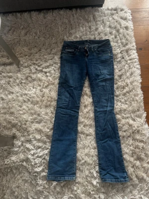 Blå bootcut jeans med låg midja - Säljer ett par klassiska blå bootcut jeans med låg midja och fem fickor. Jeansen har en snygg tvätt och är tillverkade i denim med lätt stretch. Passar perfekt till en avslappnad stil och är riktigt bekväma. De är från LTB i modellen Valerie. De är storlek 24/34