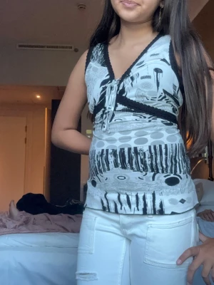 Svartvit mönstrad babydoll tank - Y2K svartvit babydoll tank 2000-tal 🖤 Patchwork print med prickar, ränder och grafiskt mönster. V-ringad med knytband och spetskant. Empire waist siluett som var huge 2004-2007. Tight i midjan, utsvängd nertill. Perfekt mall girl / coquette / emo scene aesthetic. Till låga jeans + flip flops. Äkta vintage vibe.