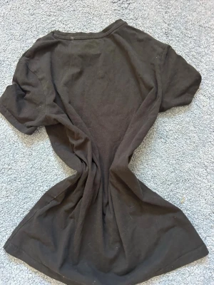 Svart basic t-shirt i bomull - En enkel svart t-shirt med rund hals och korta ärmar. Tillverkad i mjuk bomull, perfekt för en avslappnad och stilren look. Passformen är normal och t-shirten är helt utan mönster eller tryck.