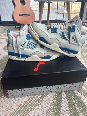 Grå och blå sneakers med meshdetaljer - Snygga sneakers i grått och blått med vita meshpaneler och detaljer i mocka. Skorna har en klassisk siluett med högt skaft, tjock sula och ventilerande mesh på sidorna. Perfekta för dig som gillar streetwear och sportig stil.