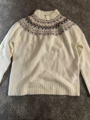 Vit stickad tröja med mönster från lager157 - Vit stickad tröja från lager157 i storlek XS med klassiskt nordiskt mönster i grått och svart runt halsen. Tröjan har ribbstickad krage, ärmslut och nederkant. Perfekt för kalla dagar och snygg till jeans eller kjol. ALDRIG ANVÄNT💕
