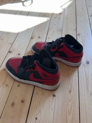 Svarta och röda sneakers Nike Air Jordan - Säljer ett par äta Nike Air Jordan sneakers i svart och rött med vit sula. Skorna har den ikoniska swoosh-loggan på sidan och Air Jordan-vingen på ankeln. Lågt skaft och snörning framtill. Perfekta för dig som gillar streetwear och sportig stil.