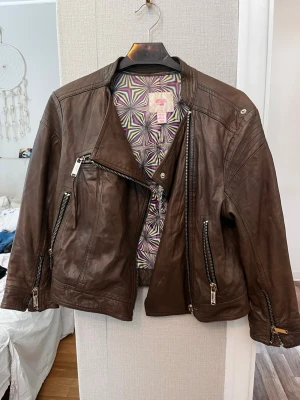 Brun skinnjacka med dragkedjor - Brun vintage skinnjacka i äkta skinn från Matthew Williamson for H&M:s limiterade designerkollektion från 2009! Storlek 40.