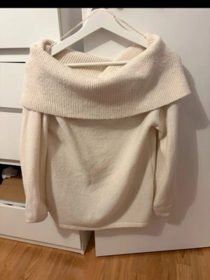 Off shoulder stickad tröja  - Tröjan har lång ärm och är gjord i ett mjukt, fluffigt material. Perfekt för kalla dagar och enkel att styla till olika outfits.