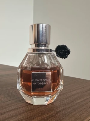 Flowerbomb parfym från Viktor & Rolf - Flowerbomb från Viktor & Rolf är en ikonisk parfym i en elegant, multifacetterad glasflaska med silverfärgat lock och svart blomdetalj. Doften har en varm, blommig ton.