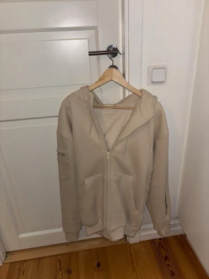 Beige zip hoodie från Comfirt XS - Säljer en beige hoodie från Comfirt i storlek XS. Hoodien har dragkedja framtill, två stora fickor och en huva. Tillverkad i mjukt material som känns skönt mot huden. Perfekt för chill dagar eller när du vill ha en enkel och clean look. viral på tt, airplane hoodie. väldigt många fickor och också dålda fickor. jätte bra o skön att ha på flyg ❤️❤️