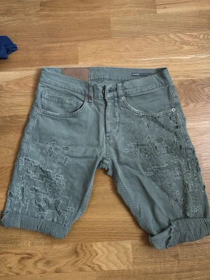 Dondup ljus gråa shorts  - Säljer ett par gröna shorts med slitna detaljer . Shortsen har fem fickor, bälteshällor och en avslappnad passform. Perfekta för dig som gillar en lite mer edgy och avslappnad stil.
