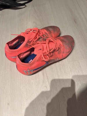 Rosa och silver fotbollsskor Nike - Säljer ett par snygga fotbollsskor från Nike i en cool mix av rosa och silver med lila detaljer. Skorna har snörning, låg profil och är tillverkade i syntetmaterial för bra grepp och känsla på planen. Perfekta för dig som vill sticka ut på matchen! Använda enbart en gång så typ nya!!